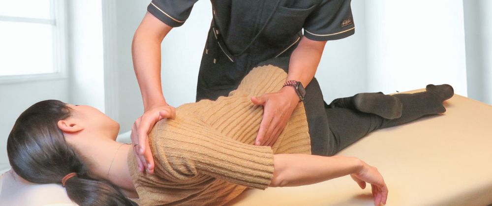 院長がベッドでお客様の背中を調整している様子